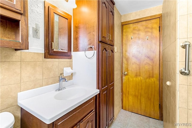 bathroom with tile patterned floors, toilet, tile walls, and vanity