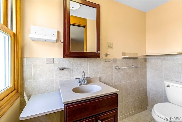 bathroom with vanity, tile walls, toilet, and a wainscoted wall