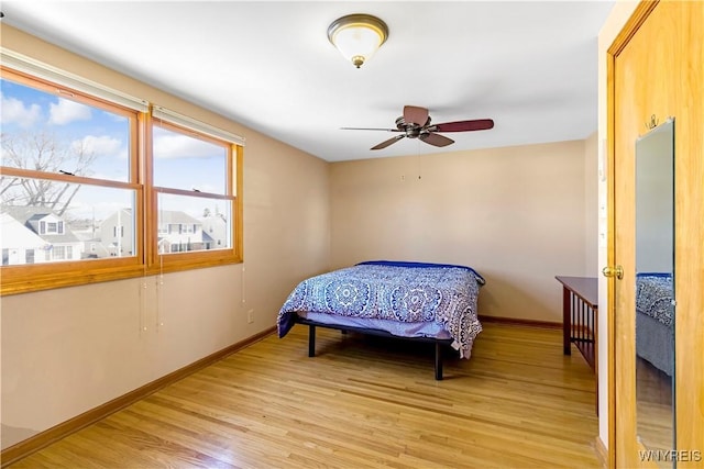 bedroom featuring light wood-style flooring, baseboards, and ceiling fan