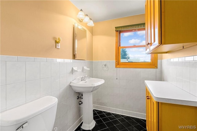 bathroom with tile patterned flooring, a wainscoted wall, toilet, and tile walls