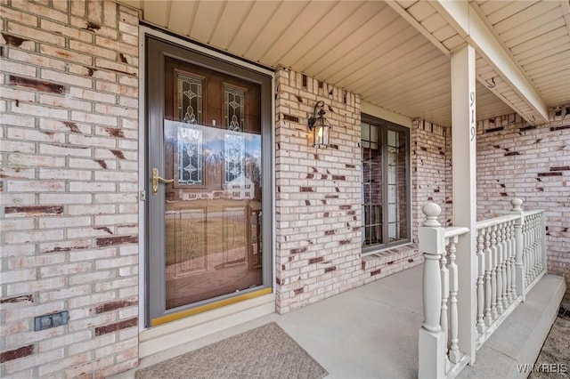 property entrance with brick siding and a porch