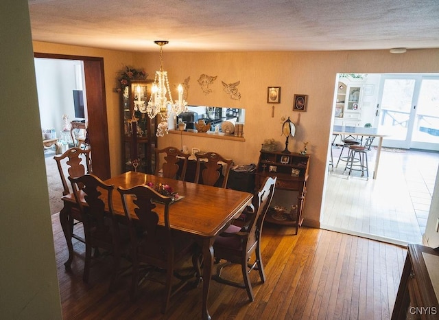 dining space featuring a notable chandelier, wood-type flooring, and a textured ceiling