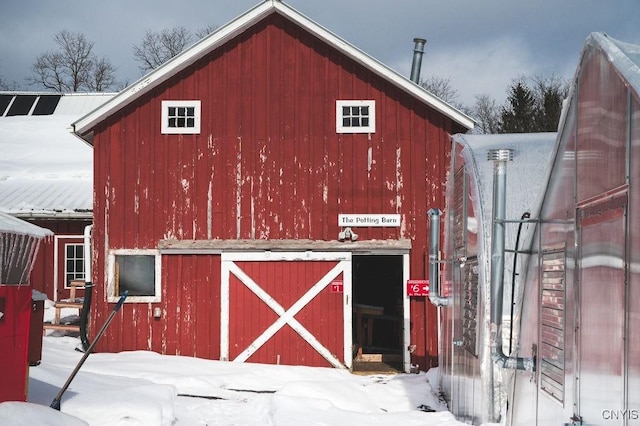 snow covered structure featuring an outbuilding and a barn