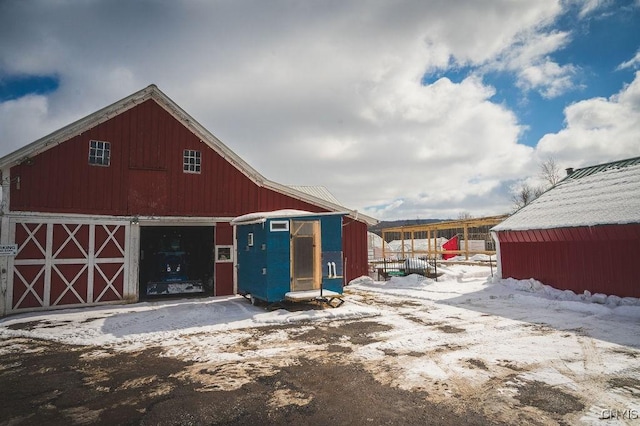 snow covered structure featuring a barn and an outdoor structure