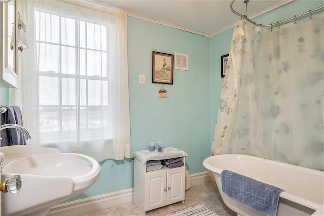 full bath featuring ornamental molding, a sink, tile patterned flooring, baseboards, and a soaking tub