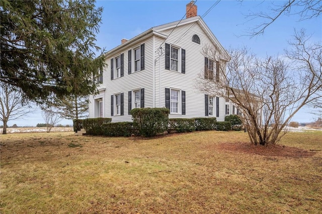 view of side of property featuring a lawn and a chimney