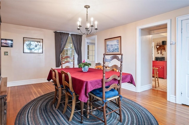 dining room with a notable chandelier, baseboards, and light wood-style floors