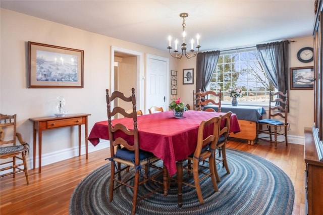 dining area featuring baseboards, an inviting chandelier, and wood finished floors