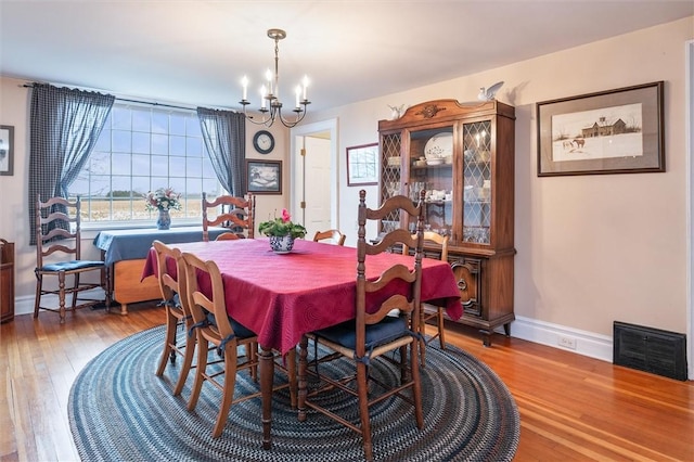 dining space with visible vents, baseboards, wood finished floors, and a chandelier