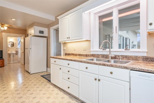 kitchen featuring a sink, white appliances, white cabinets, light countertops, and light floors