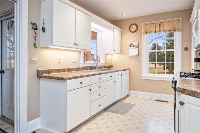 kitchen featuring a sink, light floors, white cabinets, and white dishwasher