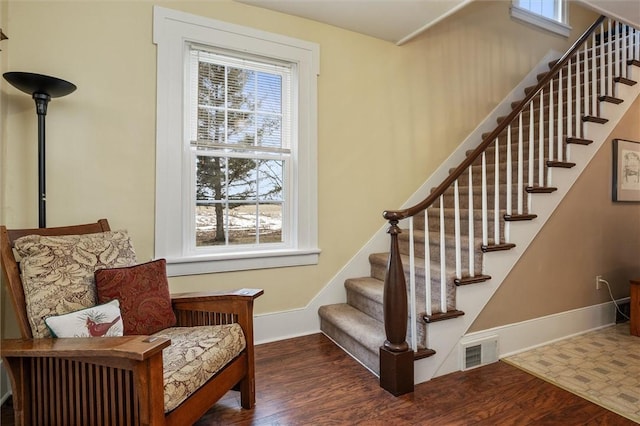 stairs featuring wood finished floors, visible vents, and baseboards