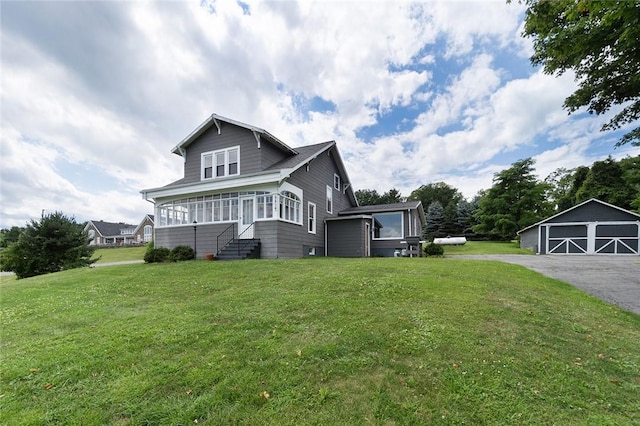 view of front facade with a garage, an outdoor structure, a front lawn, and a sunroom