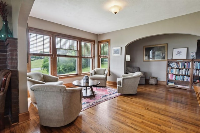 living area featuring hardwood / wood-style flooring, baseboards, and arched walkways