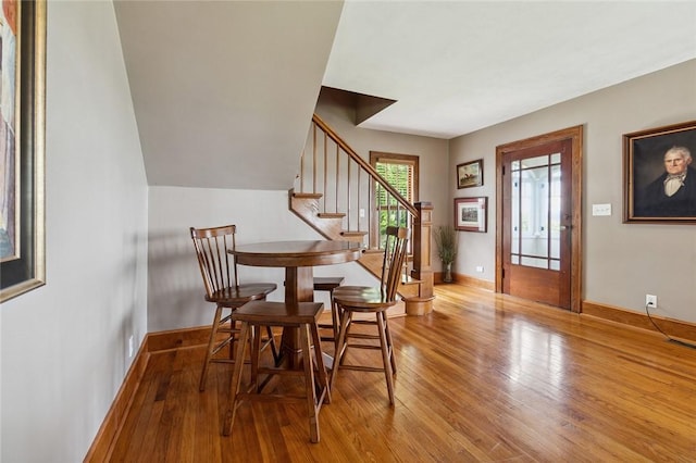 dining space with stairway, baseboards, and hardwood / wood-style flooring