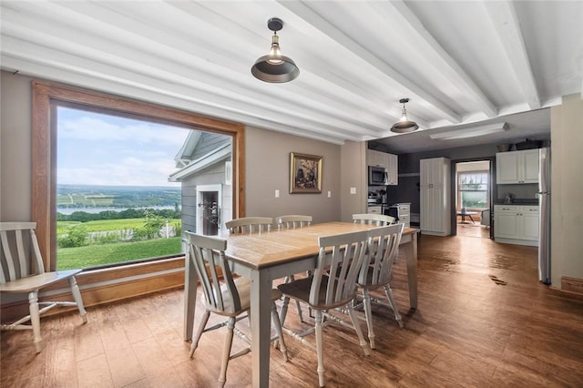 dining space with beamed ceiling and wood finished floors