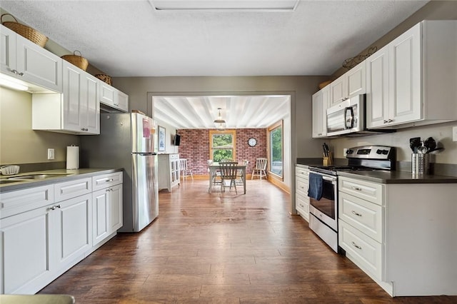 kitchen with dark countertops, white cabinets, stainless steel appliances, and dark wood-type flooring