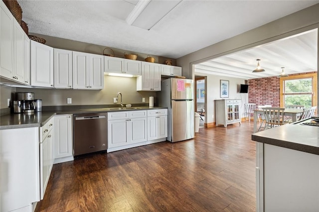 kitchen featuring a sink, dark countertops, dark wood finished floors, and stainless steel appliances