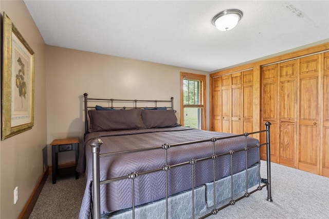 bedroom with two closets, baseboards, and carpet floors