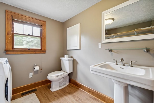 bathroom featuring visible vents, a textured ceiling, toilet, and wood finished floors