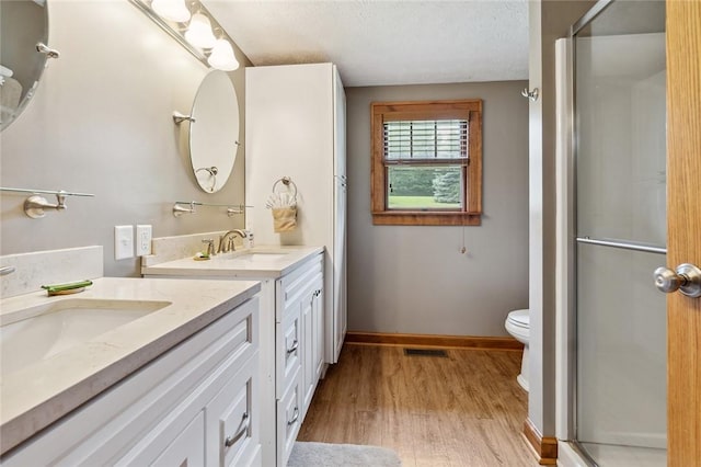 bathroom with visible vents, a stall shower, wood finished floors, baseboards, and vanity