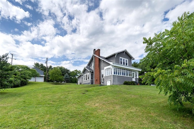 view of side of home with a lawn and a chimney