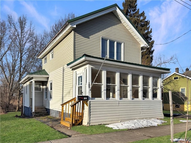 view of front of house with a front yard and a sunroom