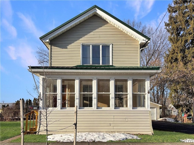 view of side of home with a lawn and a sunroom