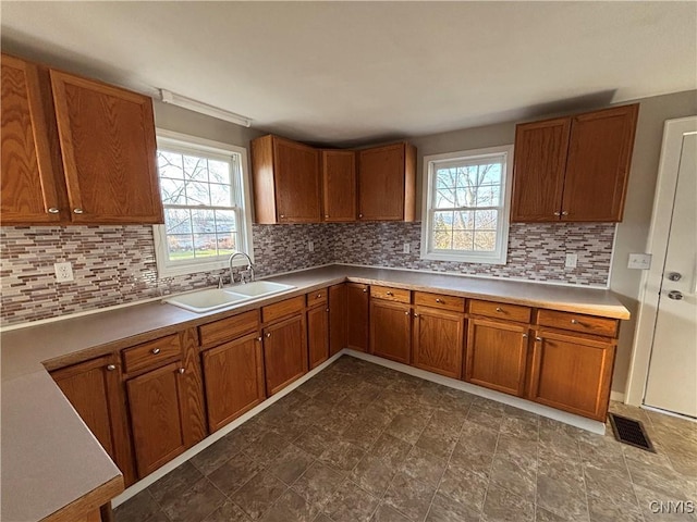 kitchen with visible vents, brown cabinets, decorative backsplash, and a sink