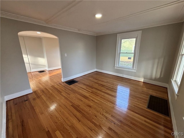 empty room featuring arched walkways, visible vents, and ornamental molding