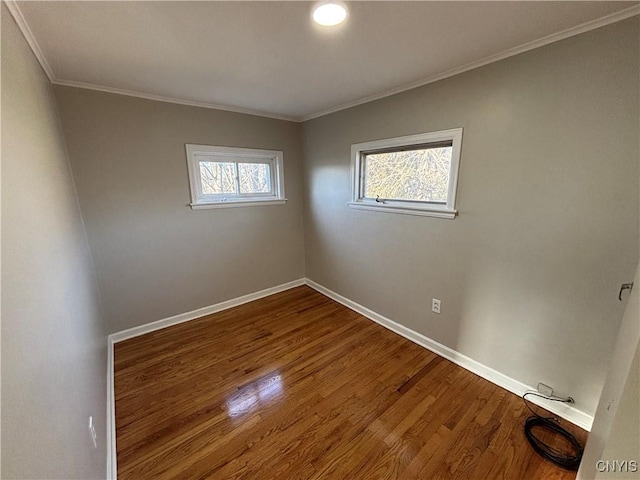 spare room featuring crown molding, wood finished floors, and baseboards