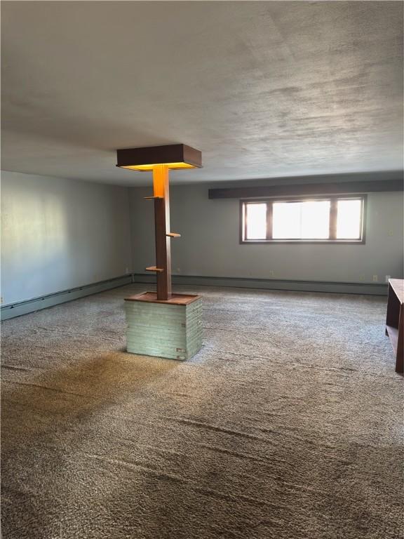 unfurnished living room with a baseboard radiator and carpet floors