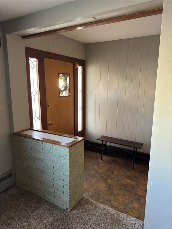 entryway featuring a baseboard radiator and wooden walls