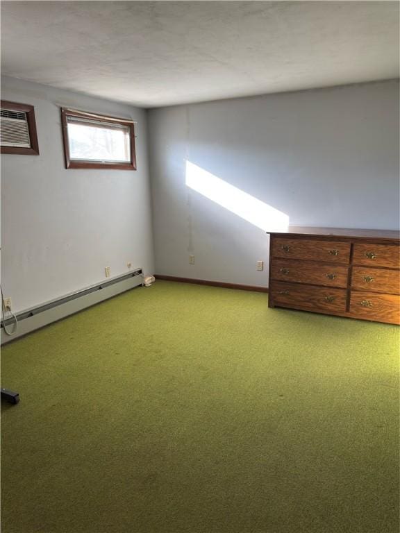 spare room featuring baseboard heating, light colored carpet, a wall mounted AC, and baseboards