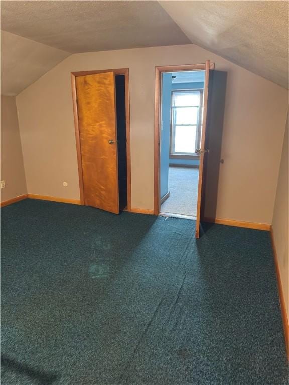 bonus room with vaulted ceiling, carpet flooring, baseboards, and a textured ceiling