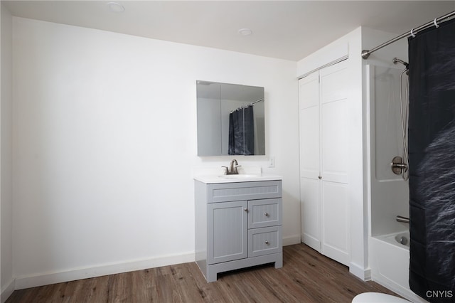 bathroom featuring vanity, wood finished floors, shower / bath combo with shower curtain, and baseboards