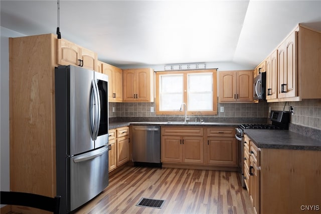 kitchen featuring a sink, dark countertops, light brown cabinets, and stainless steel appliances