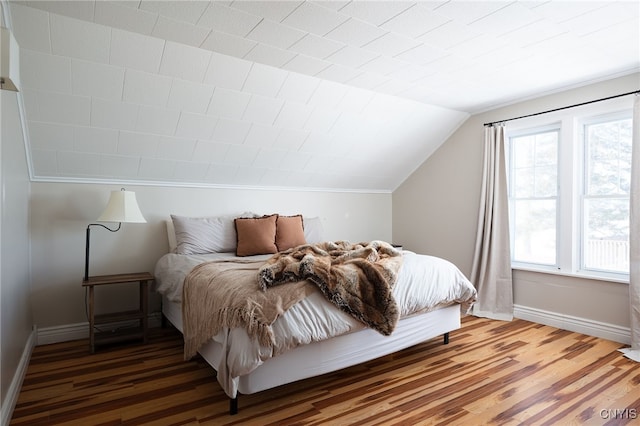 bedroom featuring vaulted ceiling, wood finished floors, and baseboards