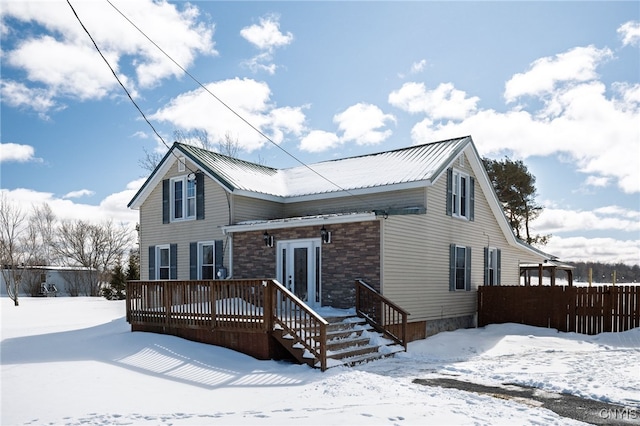 view of front of home with metal roof, a wooden deck, and fence