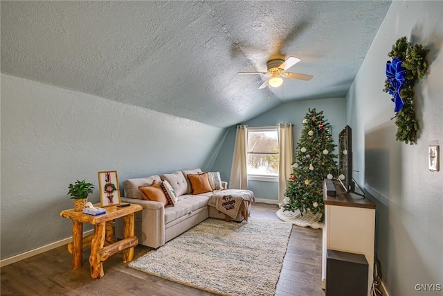 living area with a ceiling fan, baseboards, lofted ceiling, hardwood / wood-style flooring, and a textured ceiling