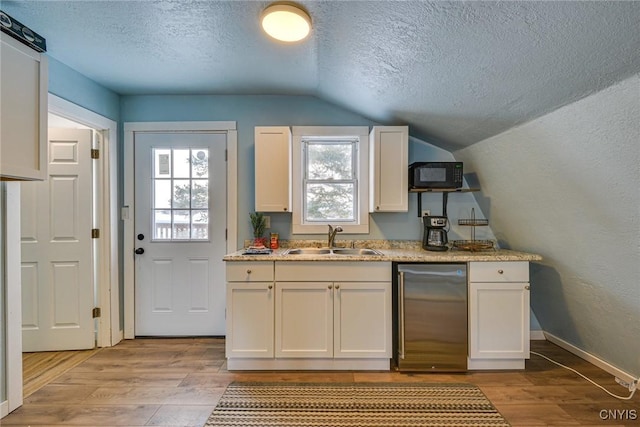 kitchen with light wood-style floors, high end refrigerator, black microwave, and a sink