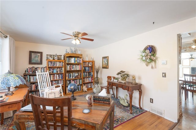 interior space featuring visible vents, baseboards, a ceiling fan, and wood finished floors