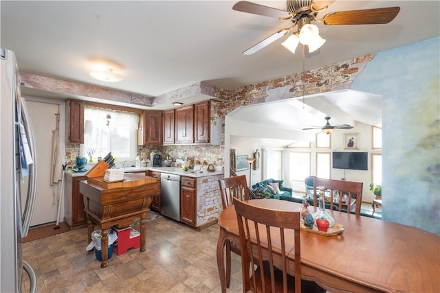 kitchen featuring stone finish flooring, tasteful backsplash, stainless steel appliances, arched walkways, and light countertops