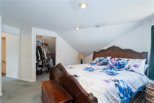 bedroom with baseboards, vaulted ceiling, a closet, a walk in closet, and carpet flooring