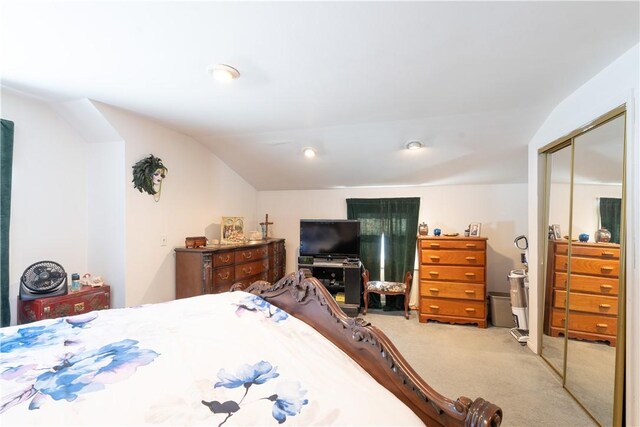 bedroom with lofted ceiling, a closet, and carpet floors