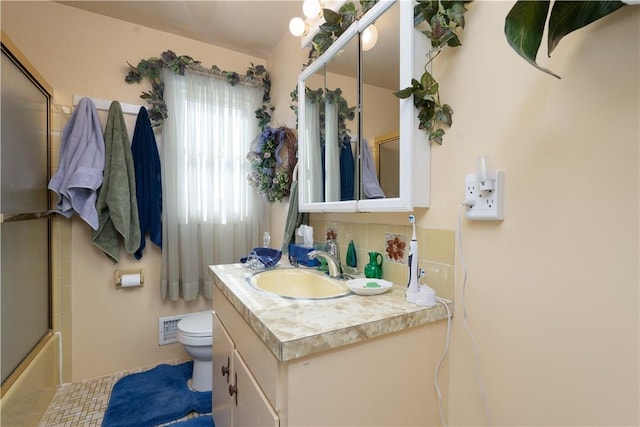 full bath featuring visible vents, toilet, backsplash, shower / bath combination with glass door, and vanity