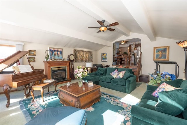 carpeted living area with a glass covered fireplace, vaulted ceiling with beams, and a ceiling fan