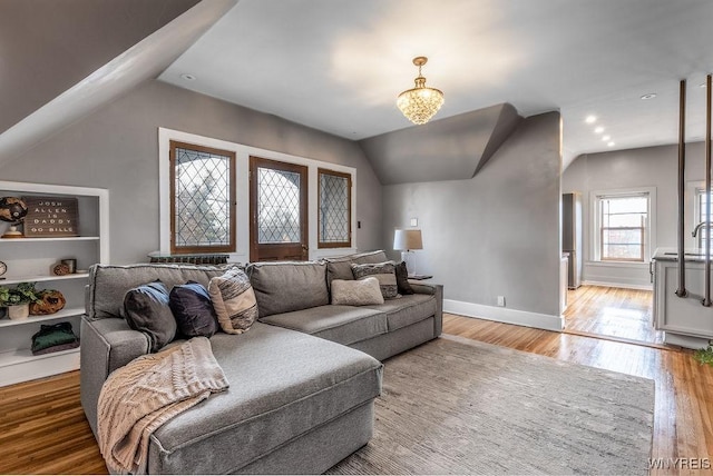 living area with baseboards, wood finished floors, and vaulted ceiling