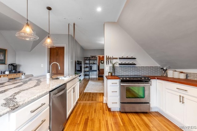 kitchen with a sink, stainless steel appliances, lofted ceiling, and white cabinetry