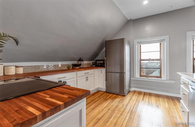 kitchen featuring butcher block countertops, white cabinetry, freestanding refrigerator, light wood finished floors, and lofted ceiling